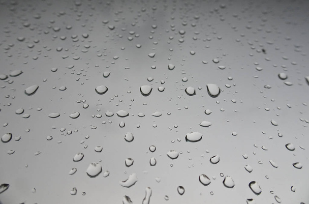 Μεγάλες σταγόνες βροχής στο παρμπρίζ του αυτοκινήτου. Υφή σταγονιδίων νερού σε γυαλί - Φωτογραφία, εικόνα