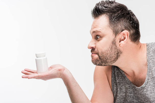 вид збоку надмірної ваги чоловік тримає пляшку ліків ізольовано на білому
 - Фото, зображення