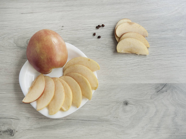 Terveellinen ruoka: omenaviipaleet valkoisella lautasella, omenoiden jyvät puisella harmaalla pohjalla. Huippunäkymä. Kopioi tila
 - Valokuva, kuva