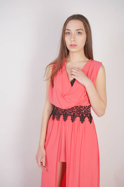 charming young girl in red evening long dress with black lace stands on a white background in the Studio - Photo, Image