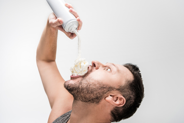gordito hombre rociando crema batida en la boca en blanco
 - Foto, imagen