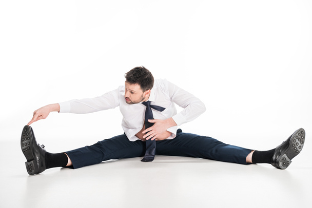 overweight man in tight formal wear sitting and stretching on white - Foto, Imagem