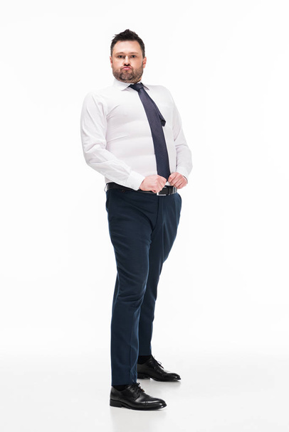 overweight man in tight formal wear looking at camera and posing on white - Fotó, kép