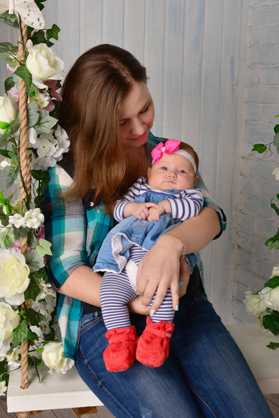 schöne junge Mutter mit Baby-Mädchen posiert auf Schaukel  - Foto, Bild