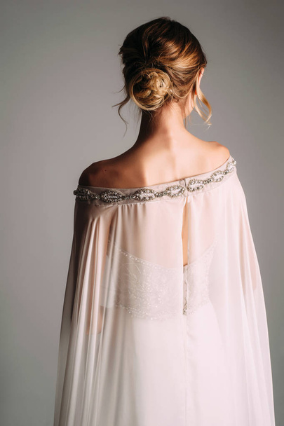 Nevěsta v bílých svatebních šatech s elegantní krajkou a lesklými krystaly ve fotostudiu. Krásný závoj, krajkové šaty a svatební účes - Fotografie, Obrázek