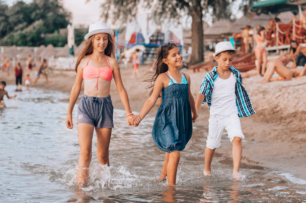 Boldog gyermekek, együtt sétált a tengerparton, és a gazdaság h - Fotó, kép