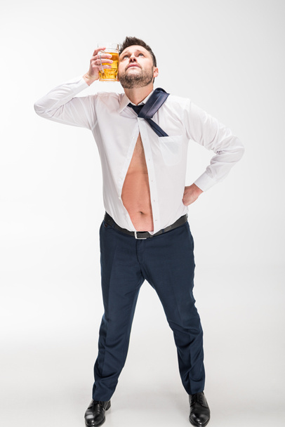 hombre con sobrepeso sosteniendo vaso de cerveza cerca de la cara en blanco
 - Foto, imagen