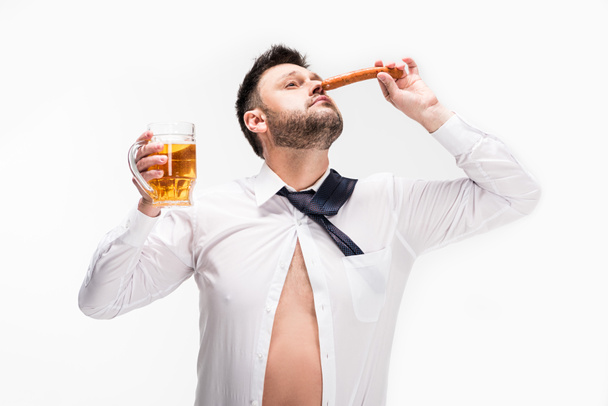 υπέρβαρο άνθρωπος με μάτια κλειστά οσμή άρωμα λουκάνικου και κρατώντας ένα ποτήρι μπύρας απομονώνεται σε λευκό - Φωτογραφία, εικόνα