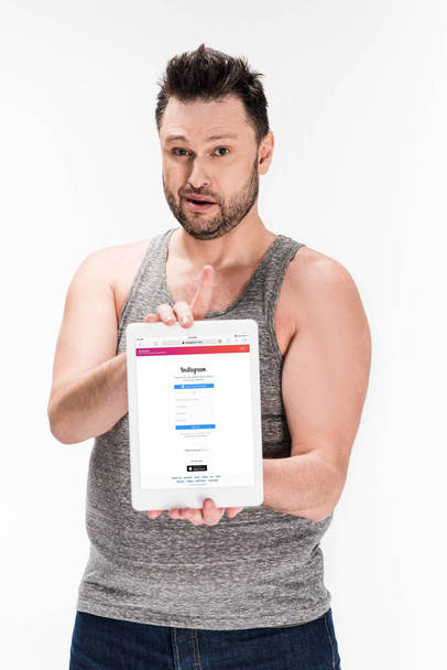 overweight man looking at camera and showing digital tablet with instagram app on screen isolated on white - Foto, Imagen