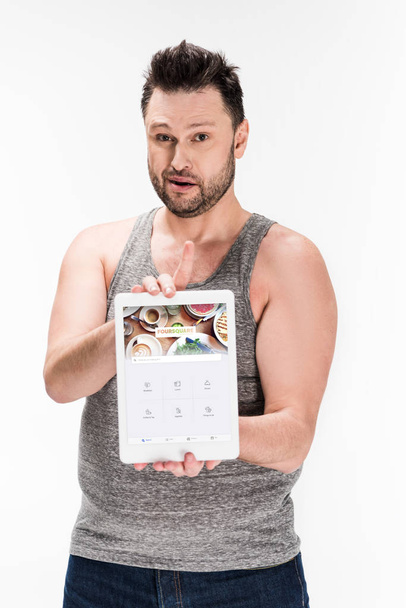 overweight man looking at camera and showing digital tablet with foursquare app on screen isolated on white - Zdjęcie, obraz