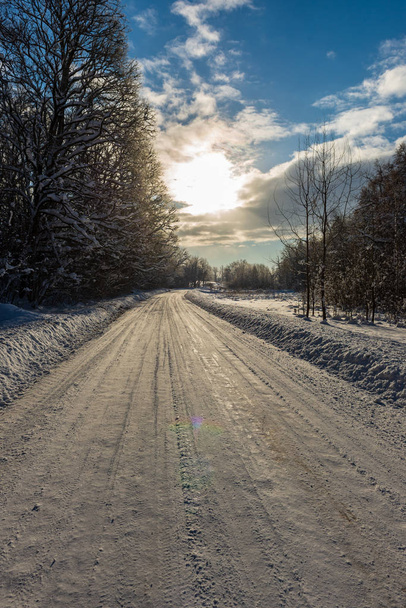 snowy winter road covered in ice and snow in forest woth blue sky - Foto, Imagem