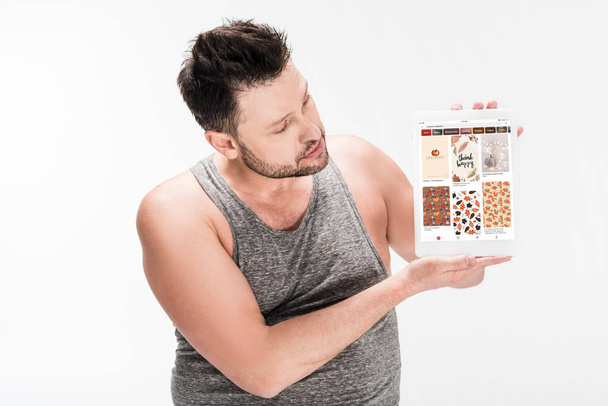 Nadváha muž zobrazující digitální tablet s Pinterest aplikací na obrazovce izolované na bílém - Fotografie, Obrázek