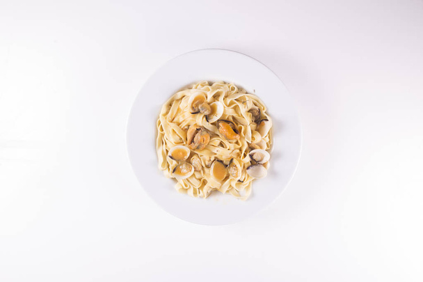prato de macarrão com mexilhões e amêijoas em fundo branco
 - Foto, Imagem