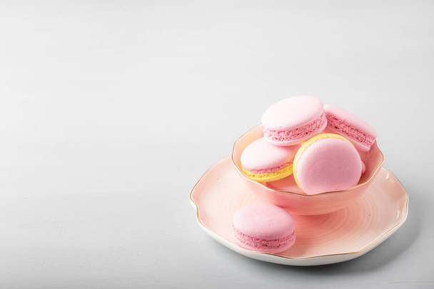 Pink yellow macaroons cakes on gray blue table background, place for text, trendy minimalism style, selective focus - Zdjęcie, obraz