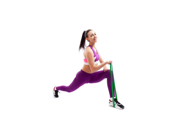 Gyönyörű fiatal nő csinál szúrást gyakorolisewith sport fitness gumiszalag a fitness tornaterem izolált fehér háttér előtt. Fit lány élő aktív életmód - Fotó, kép