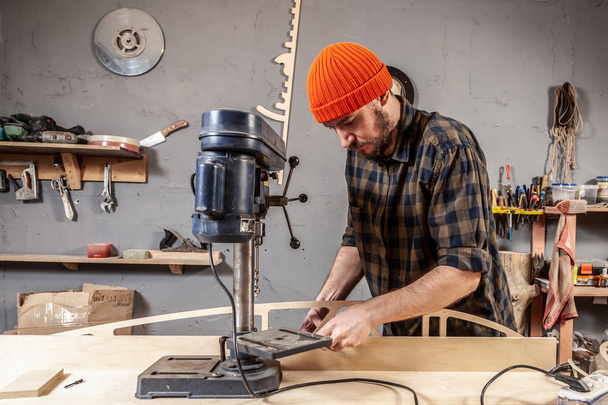 Close up of carpenter in work clothes carving a wooden on an drill. Manual job DIY inspiration improvement job fix shop helmet joinery startup idea industrial education profession career concept.  - Photo, Image