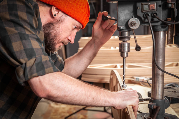 Χέρια του εργάτη ξυλουργός χρησιμοποιώντας ηλεκτρική μηχανή γεώτρησης, κοντινά πλάνα. Χειρωνακτική εργασία DIY έμπνευση βελτίωση δουλειά Fix κατάστημα κράνος ξυλουργείο εκκίνηση ιδέα βιομηχανική εκπαίδευση επάγγελμα καριέρα concept - Φωτογραφία, εικόνα
