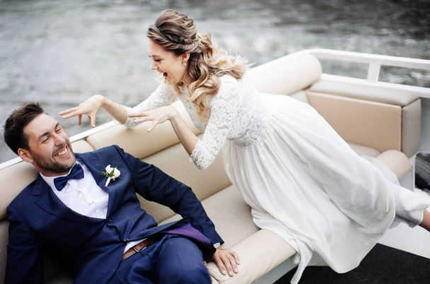 stylish bride and groom on their wedding day, having fun and smiling on a boat trip on the river  - Foto, immagini