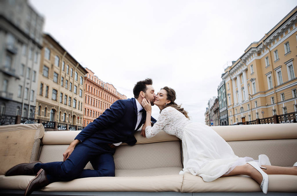 stylish bride and groom on their wedding day, having fun and kissing on a boat trip on the river  - Foto, Imagem