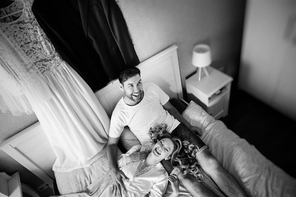 morning of the bride and groom, lovers lying and laughing in the bedroom, black and white photo  - Φωτογραφία, εικόνα