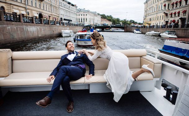 stylish bride and groom on their wedding day, having fun and smiling on a boat trip on the river  - Foto, immagini