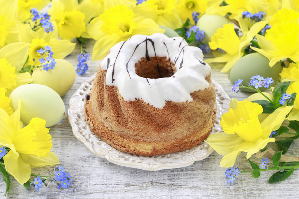 Traditional easter cake and bouquet of daffodils in the backgrou - Φωτογραφία, εικόνα