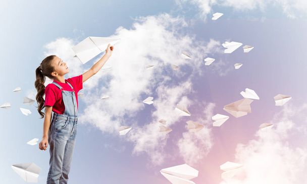 Petite fille mignonne sur fond de ciel jouant avec avion en papier
 - Photo, image