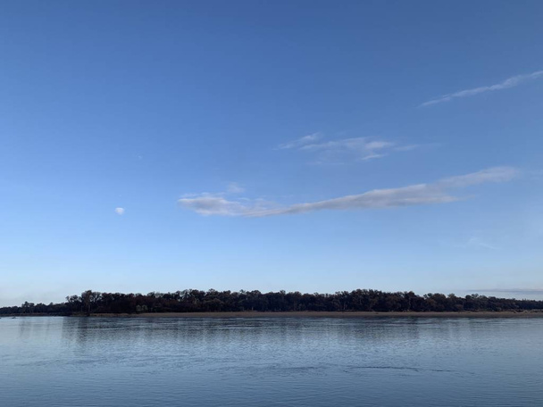 Το πρωί στις όχθες του ποταμού Σίρ Ντάρυα. Η υφή της επιφάνειας του νερού. Συννεφιασμένος ουρανός πάνω από το ποτάμι. Βλάστηση στις όχθες του ποταμού. - Φωτογραφία, εικόνα