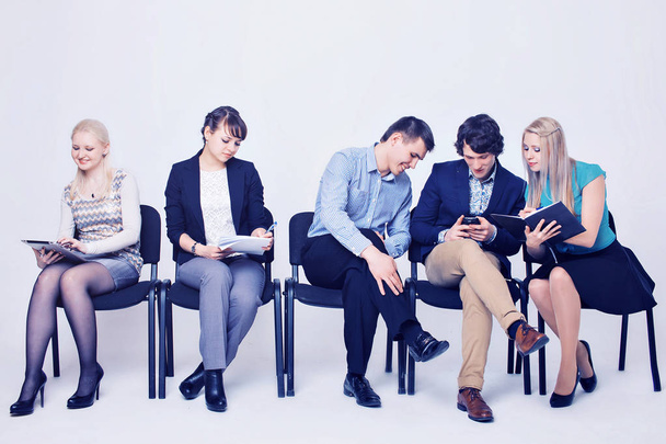 business people waiting in queue sitting in row holding smartphones and cvs, human resources, employment and hiring concept - Foto, Bild