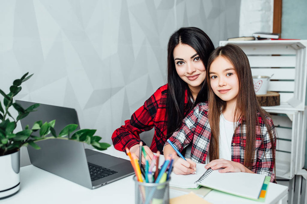 Two sisters doing homework at home, focus on foreground - Фото, изображение
