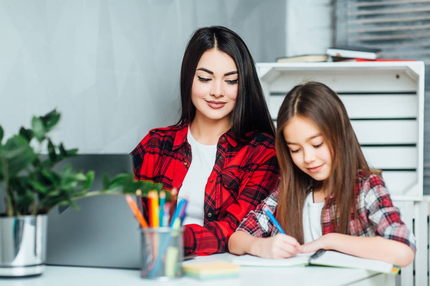 Two sisters doing homework at home, focus on foreground - Фото, изображение