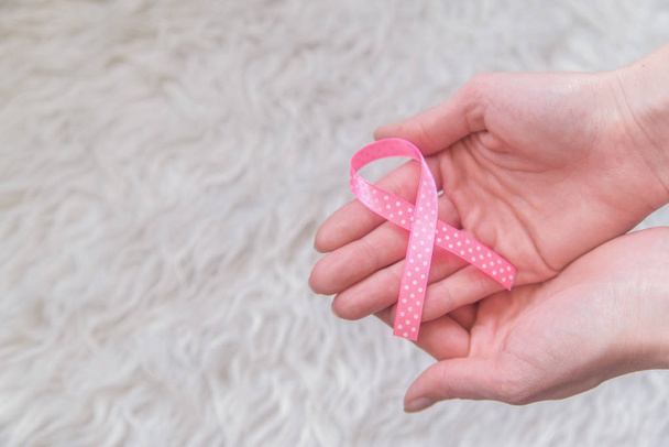 Womans hands holding pink ribbon on white background, breast cancer awareness month, concept of health.  - Photo, Image