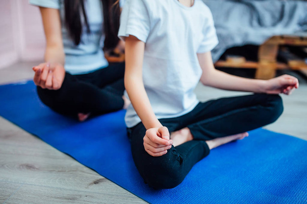 vista recortada de hermanas haciendo ejercicios en esterilla de yoga en casa, se centran en primer plano
 - Foto, Imagen