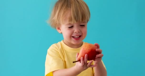 Sweet little boy smiles whith red pear - Footage, Video
