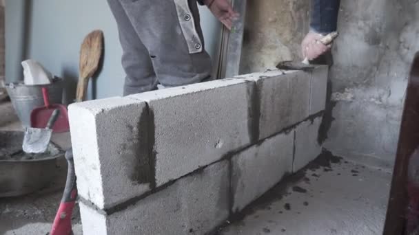 Trabalhador da construção constrói parede de tijolo, vista close-up no canteiro de obras
 - Filmagem, Vídeo