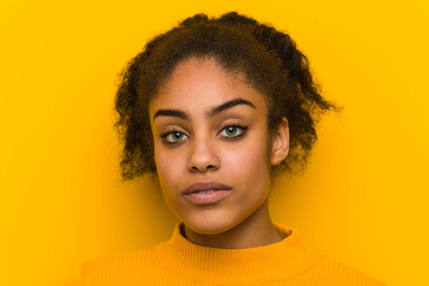 Young black woman closeup over an orange wall - Foto, afbeelding