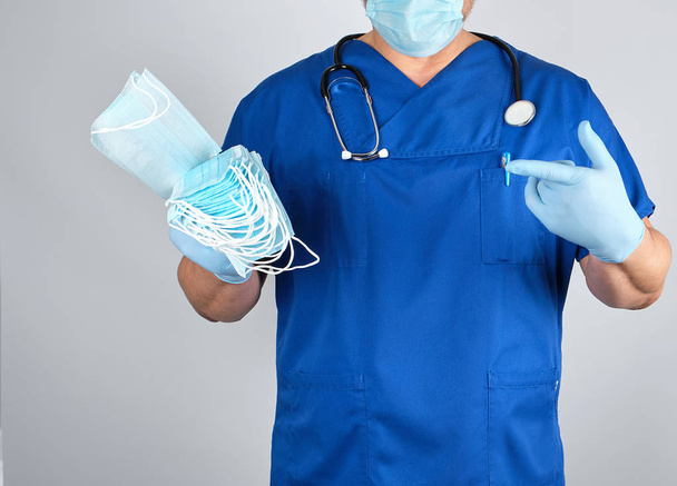 medico in uniforme e in guanti di lattice blu mantiene maschere sterili
 - Foto, immagini