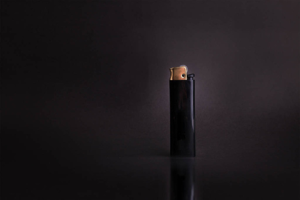 schwarzes Feuerzeug auf schwarzem Hintergrund mit Kopierraum - Foto, Bild