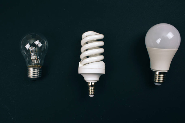 Recycling, reuse, reduce concept. Protect an environment. Single-use different light bulbs in the row on dark background, top view. Single-use electric waste - Photo, Image
