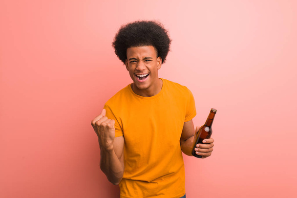 Молодой африканский американец с пивом удивлен и шокирован
 - Фото, изображение