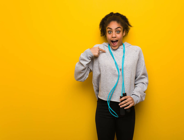 Young fitness black woman surprised, feels successful and prosperous. Holding a jump rope. - Photo, Image