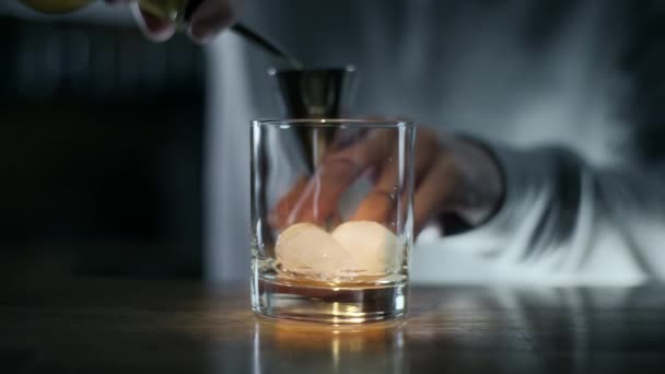 Bartender pours whiskey to the jigger and then to the glass with ice, making of alcohol drink, cocktail in the bar, bartender at work, 4k UHD 60p Prores HQ 422 - Felvétel, videó