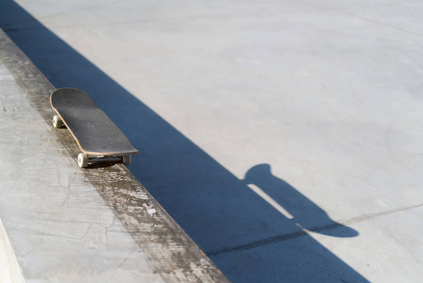 Professional skateboard laying on concrete ledge at skate park. Practice freestyle, urban extreme sport activity for youth, staying out of trouble - Photo, image