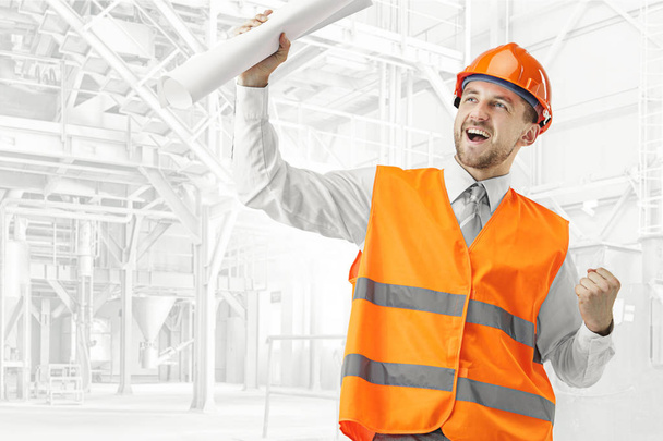 The builder in orange helmet against industrial background - Valokuva, kuva