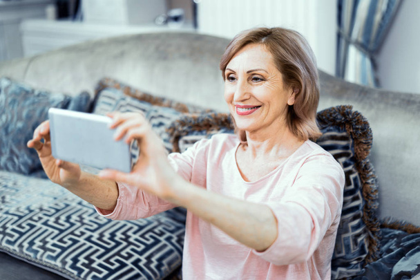 Beautiful mature woman takes selfie at home - Foto, Imagen