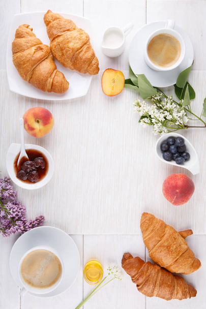 Desayuno - dos tazas de café, croissants, mermelada, miel y fruta
 - Foto, imagen