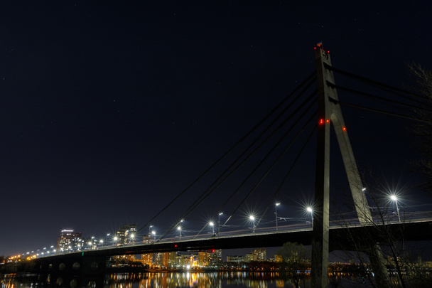 tumma kaupunkikuva valaistuilla rakennuksilla ja sillalla
  - Valokuva, kuva