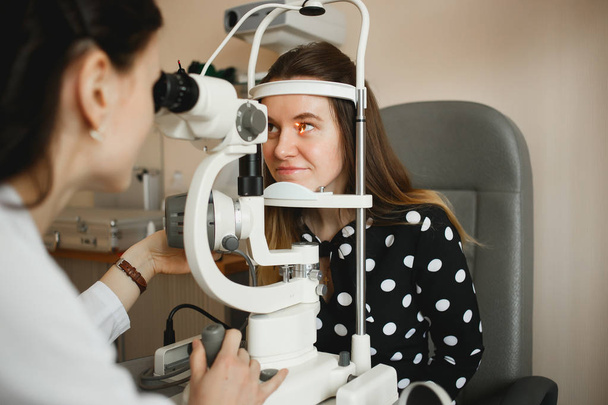 Архангельск, Россия - 25 марта 2019 года: Привлекательная женщина-врач-офтальмолог проверяет зрение молодой женщины в современной клинике. Врач и пациент офтальмологической клиники
 - Фото, изображение