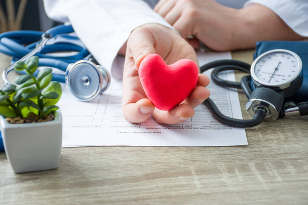 Orvos a belgyógyászat és kardiológus gazdaság a kezében, és azt mutatja, hogy a beteg alakja piros lapot szív orvosi konzultáció során. A szív, a diagnózis és a kezelés okainak magyarázata - Fotó, kép