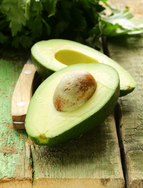 Ripe avocado cut in half on a wooden table - Photo, Image